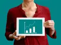 Une personne tient une tablette affichant un graphique de croissance, illustrant la méthode des moindres carrés pour analyser les tendances.