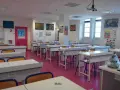 Salle de classe lumineuse avec des tables de laboratoire, des chaises et des posters scientifiques, prête pour l'enseignement scientifique.