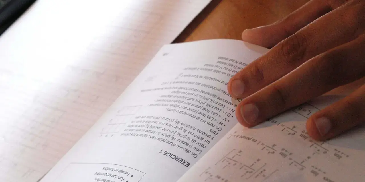 Main d'un étudiant sur un livre de maths, concentré sur le sujet maths jour 2. Formules et exercices à résoudre.