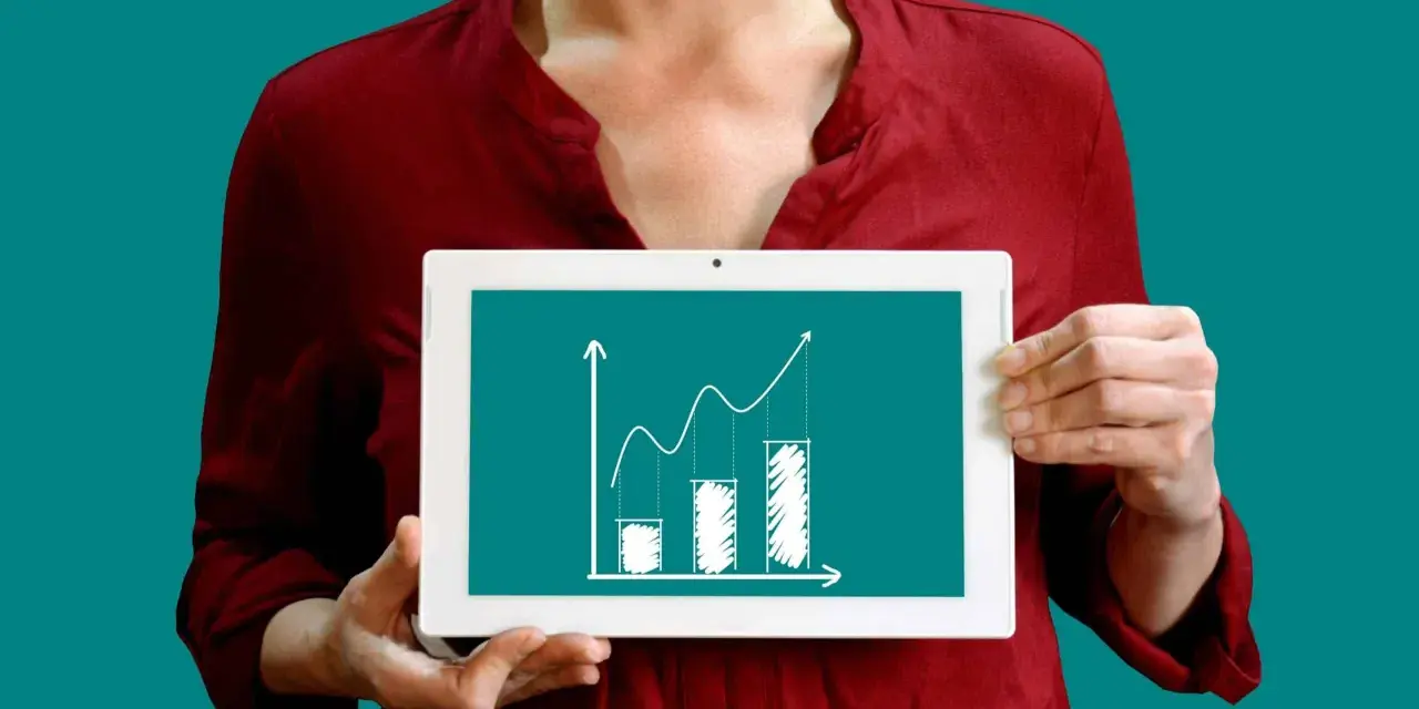Une personne tient une tablette affichant un graphique de croissance, illustrant la méthode des moindres carrés pour analyser les tendances.