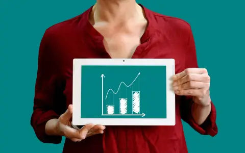 Une personne tient une tablette affichant un graphique de croissance, illustrant la méthode des moindres carrés pour analyser les tendances.