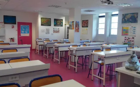 Salle de classe lumineuse avec des tables de laboratoire, des chaises et des posters scientifiques, prête pour l'enseignement scientifique.