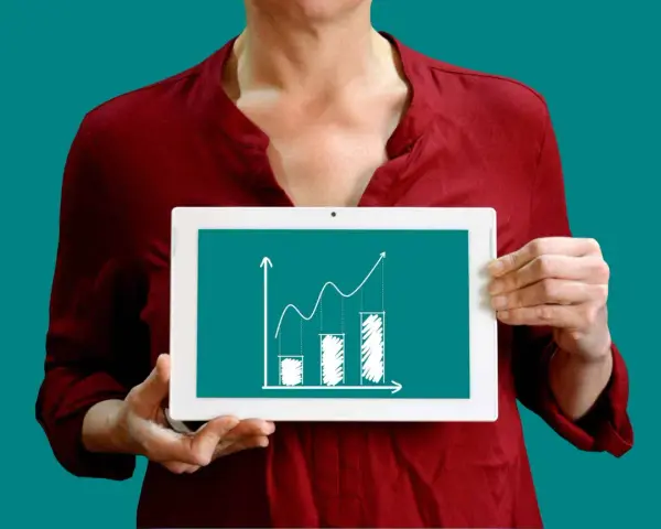Une personne tient une tablette affichant un graphique de croissance, illustrant la méthode des moindres carrés pour analyser les tendances.