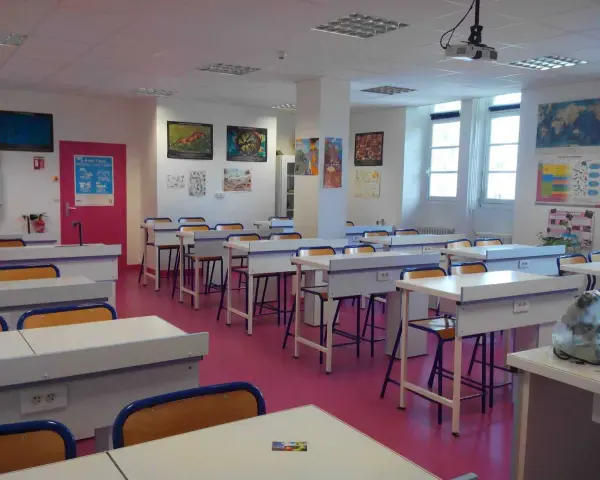 Salle de classe lumineuse avec des tables de laboratoire, des chaises et des posters scientifiques, prête pour l'enseignement scientifique.