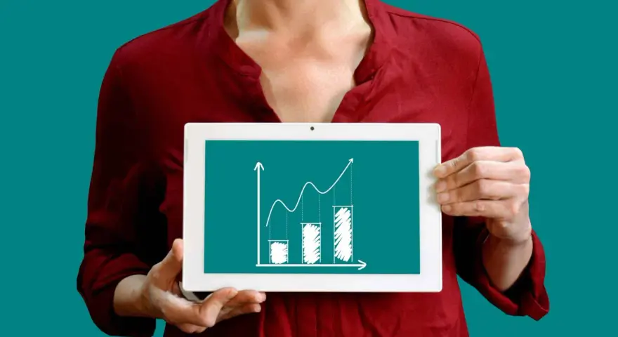 Une personne tient une tablette affichant un graphique de croissance, illustrant la méthode des moindres carrés pour analyser les tendances.