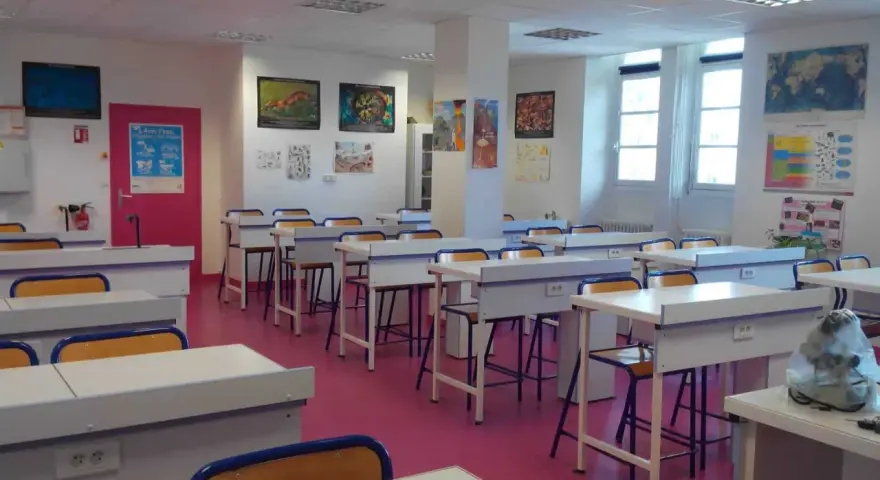 Salle de classe lumineuse avec des tables de laboratoire, des chaises et des posters scientifiques, prête pour l'enseignement scientifique.