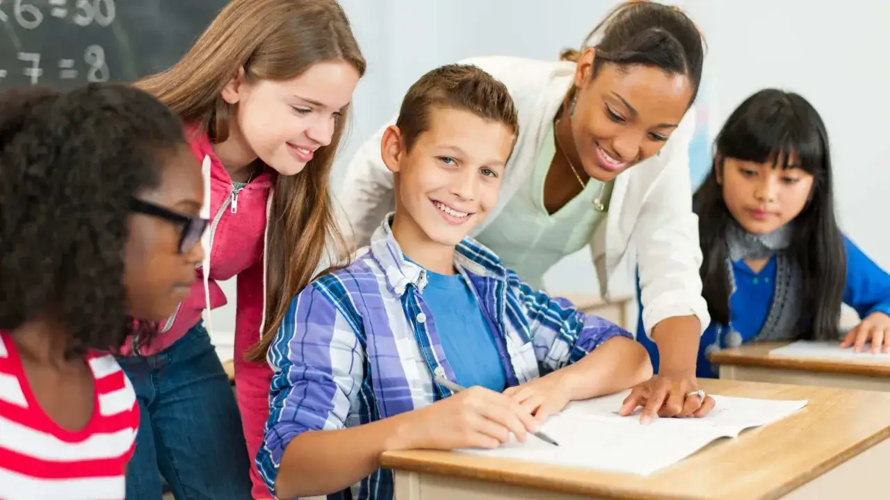 Des &eacute;l&egrave;ves travaillent en classe, concentr&eacute;s sur leurs exercices. L'enseignante les aide, sachant que le brevet est obligatoire pour passer en seconde.